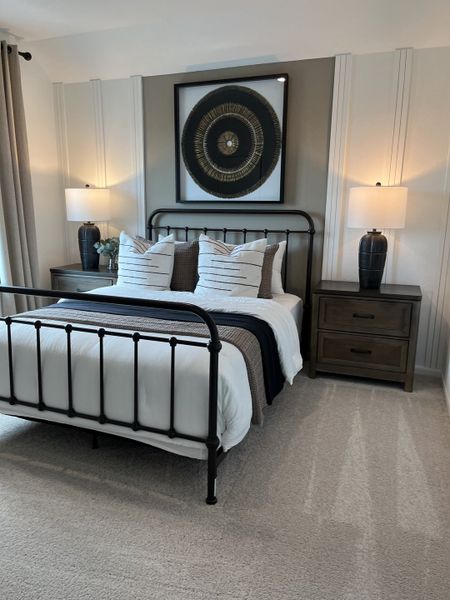 A cozy bedroom featuring a metal bed frame, elegant artwork, and modern nightstands with stylish lamps.