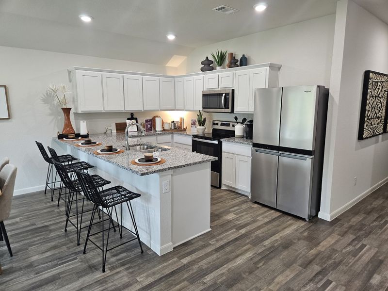 A modern kitchen with sleek stainless steel appliances, white cabinets, and a stylish breakfast bar.
