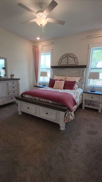 A cozy bedroom with a rustic white bed frame, plush pillows, and ample natural light.