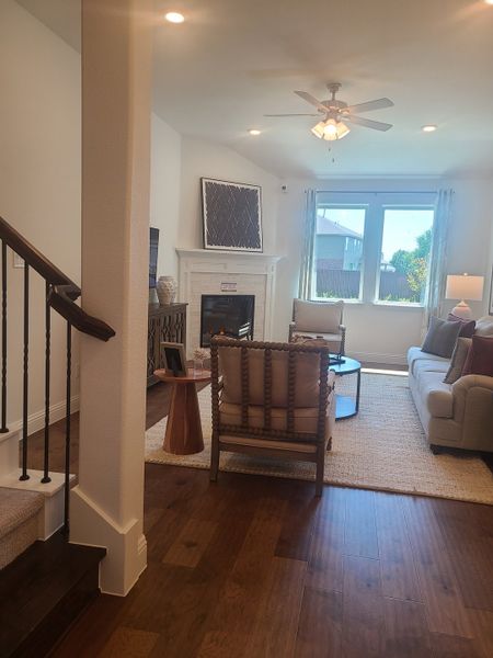 A cozy living room with hardwood floors, a white fireplace, and modern furniture. Bright, airy ambiance with ample natural light.