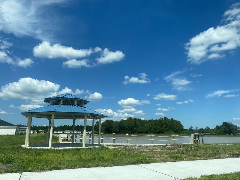A charming gazebo with a blue roof overlooking a scenic lake in Cypress Meadows - Signature Series by Meritage Homes (Jacksonville, FL).
