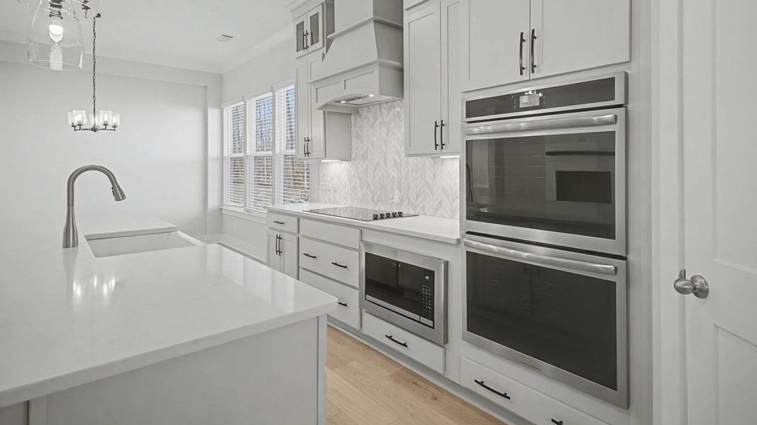 Kitchen with a double stove, light grey cabinetry, beautiful tile backsplash, and stunning view of dining area Kitchen with a double stove, light grey cabinetry, beautiful tile backsplash, and stunning view of dining area
