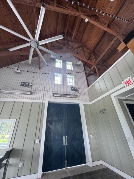 A rustic interior featuring vaulted wood ceilings, large dark doors, and modern lighting with a spacious, airy atmosphere.