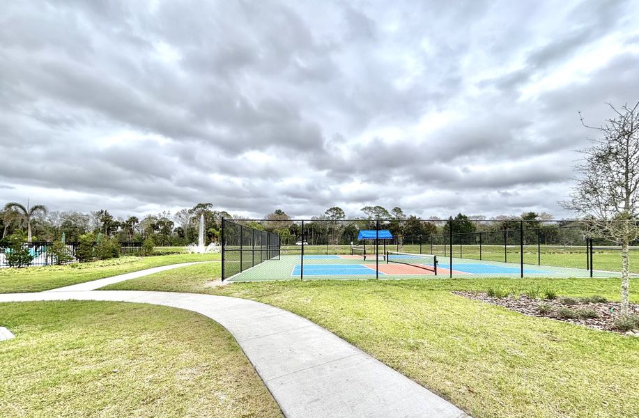 A vibrant tennis court in scenic Naples Village at Verona I by KB Home, set against lush landscapes in Titusville, FL.