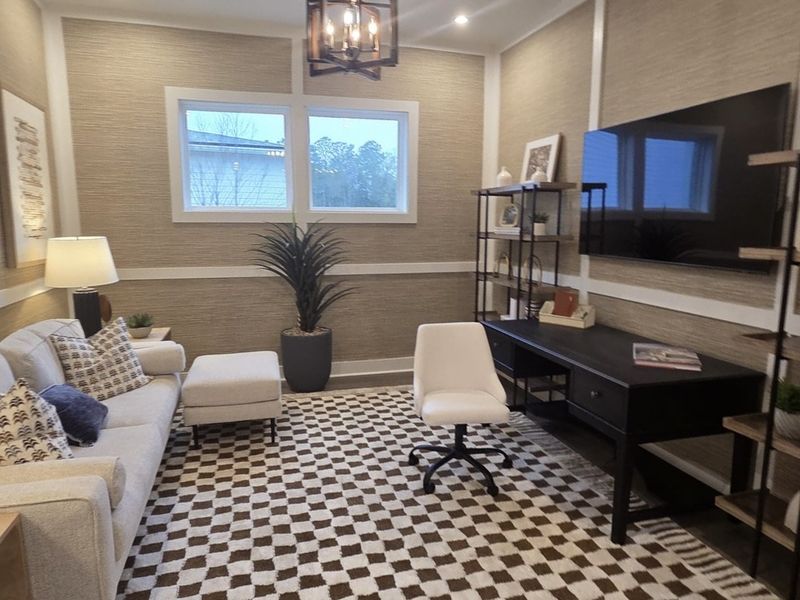 A cozy home office with a patterned rug, sleek desk, and comfortable seating.