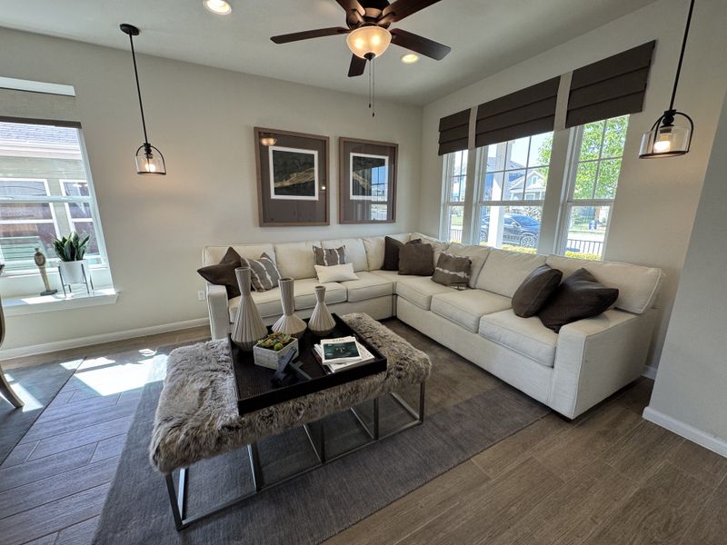 A cozy living room featuring a plush sectional, elegant pendant lights, and large windows for ample natural light. A cozy living room featuring a plush sectional, elegant pendant lights, and large windows for ample natural light.