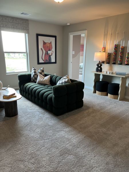 A cozy living space featuring a plush green sofa, playful cat artwork, and modern decor elements.