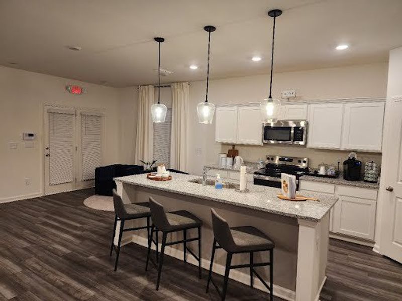 A modern kitchen with sleek cabinetry, granite countertops, and pendant lighting over a spacious island with bar seating.