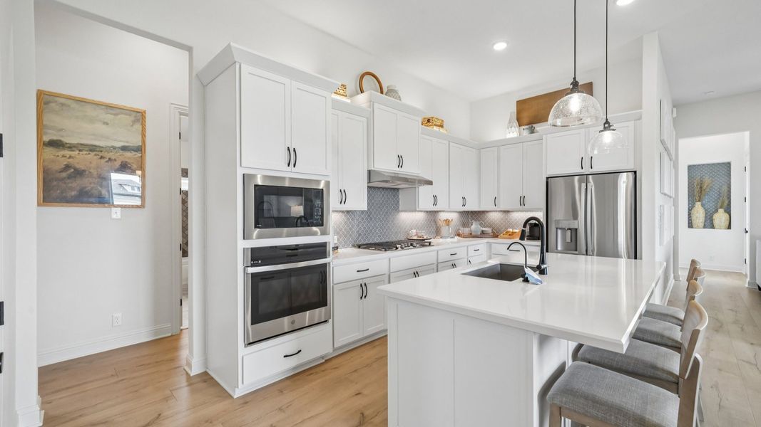 Sleek kitchen design with gas cooktop, vent hood, built-in oven, and modern finishes Sleek kitchen design with gas cooktop, vent hood, built-in oven, and modern finishes