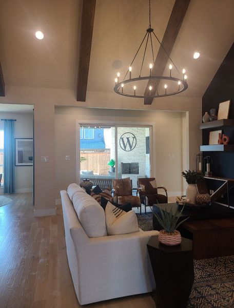 A luxurious living room with exposed beams, cozy seating, and a sleek chandelier, offering a welcoming atmosphere.