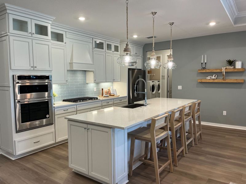 A modern kitchen with white cabinets, quartz countertops, pendant lights, and wooden bar stools, creating an inviting space. A modern kitchen with white cabinets, quartz countertops, pendant lights, and wooden bar stools, creating an inviting space.