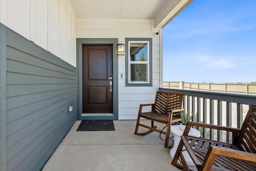 A porch with chairs and a door.