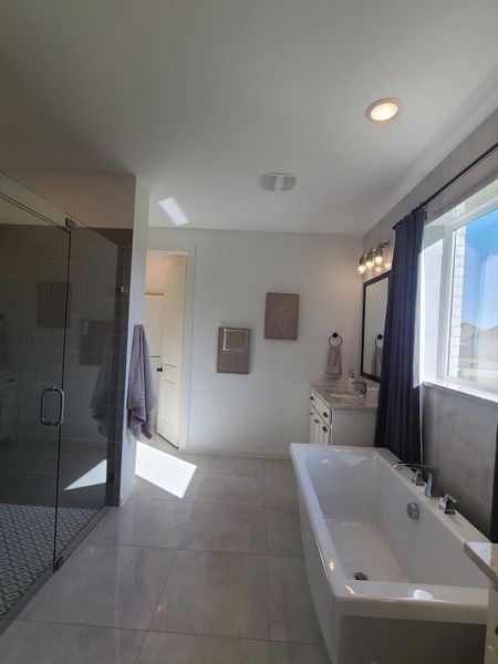 A spacious bathroom featuring a sleek glass shower, a modern freestanding tub, and elegant tile flooring.