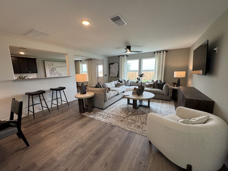 A cozy living room featuring a plush sectional, elegant lighting, and a stylish breakfast bar with high seating.