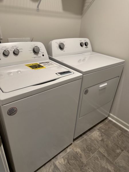 A functional laundry room featuring a modern washer and dryer set with sleek controls and tiled flooring.