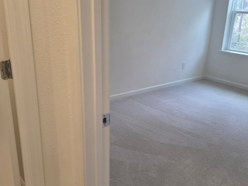 A bright room with soft carpeting and a large window letting in natural light.