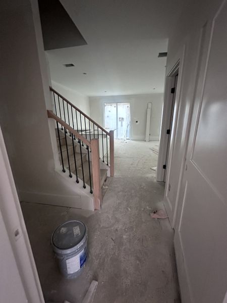 A spacious entryway leading to a staircase with elegant railing, showcasing construction progress in a modern home.