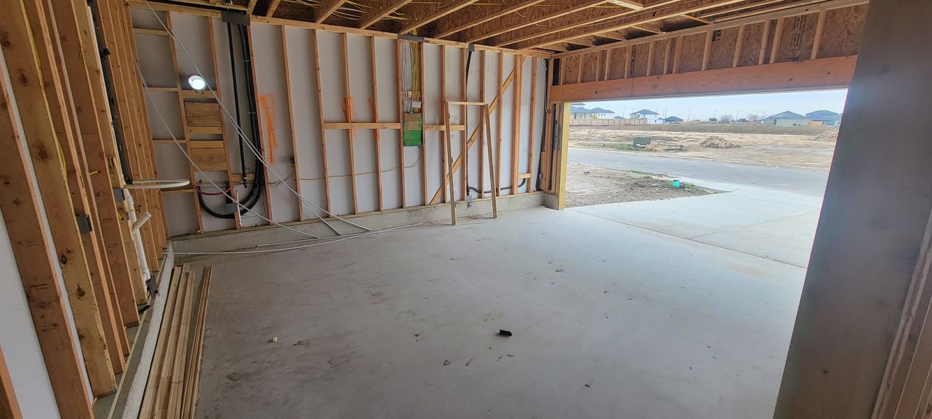 An unfinished garage space with exposed wood framing and concrete flooring.