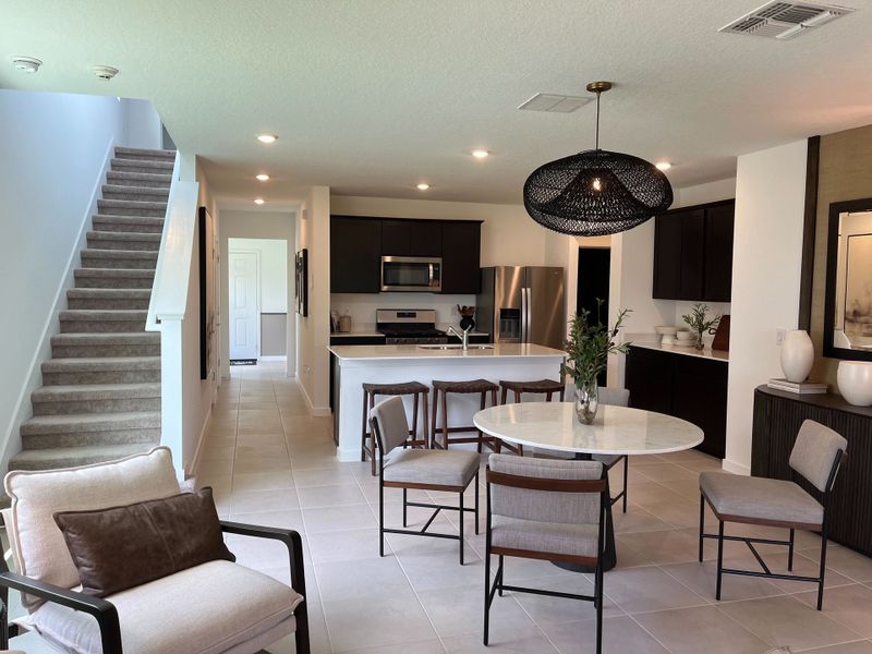 A modern open-concept living space with sleek kitchen, cozy dining area, and elegant staircase leading upstairs. A modern open-concept living space with sleek kitchen, cozy dining area, and elegant staircase leading upstairs.
