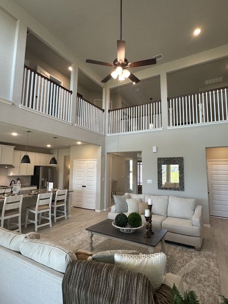 A spacious living area with high ceilings, open balcony, cozy seating, and a modern kitchen.