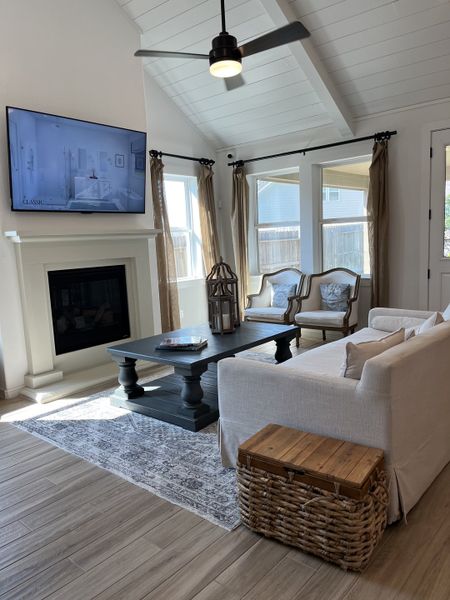 A cozy living room with a vaulted ceiling, elegant fireplace, and ample natural light from large windows. A cozy living room with a vaulted ceiling, elegant fireplace, and ample natural light from large windows.