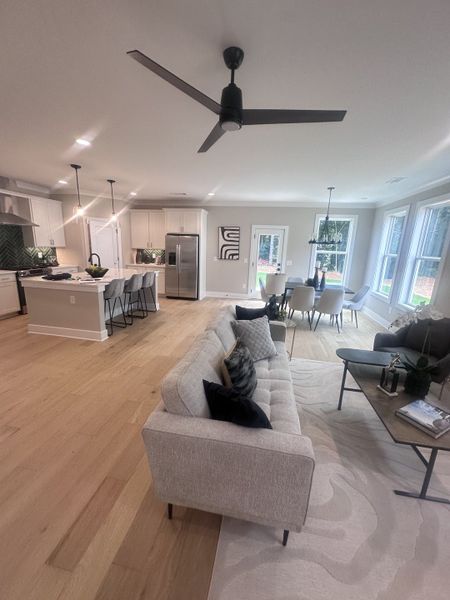 An open-concept living area featuring a light gray sofa, sleek kitchen, and elegant dining space with modern accents. An open-concept living area featuring a light gray sofa, sleek kitchen, and elegant dining space with modern accents.