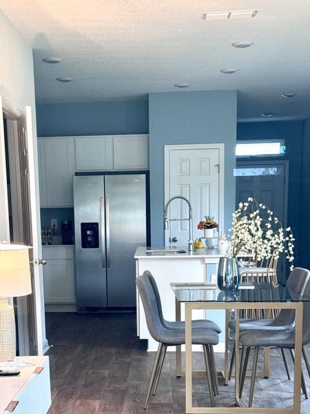 A modern kitchen with sleek stainless steel appliances, a compact dining area, and soft blue walls for a cozy feel. A modern kitchen with sleek stainless steel appliances, a compact dining area, and soft blue walls for a cozy feel.