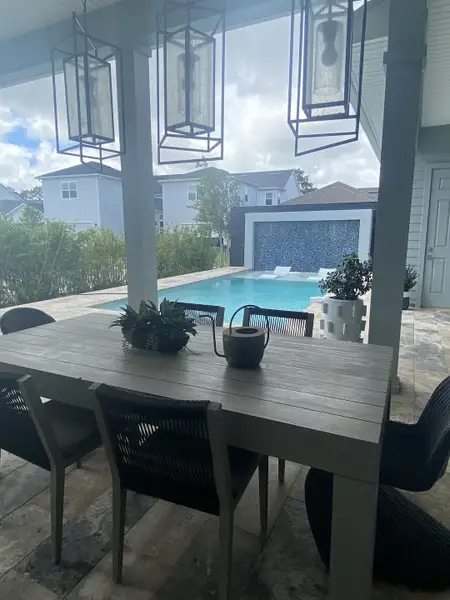 A stylish outdoor patio with a large dining table and view of a pool, perfect for entertaining and relaxation.