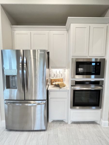A modern kitchen with sleek stainless steel appliances, white cabinetry, and a stylish backsplash.