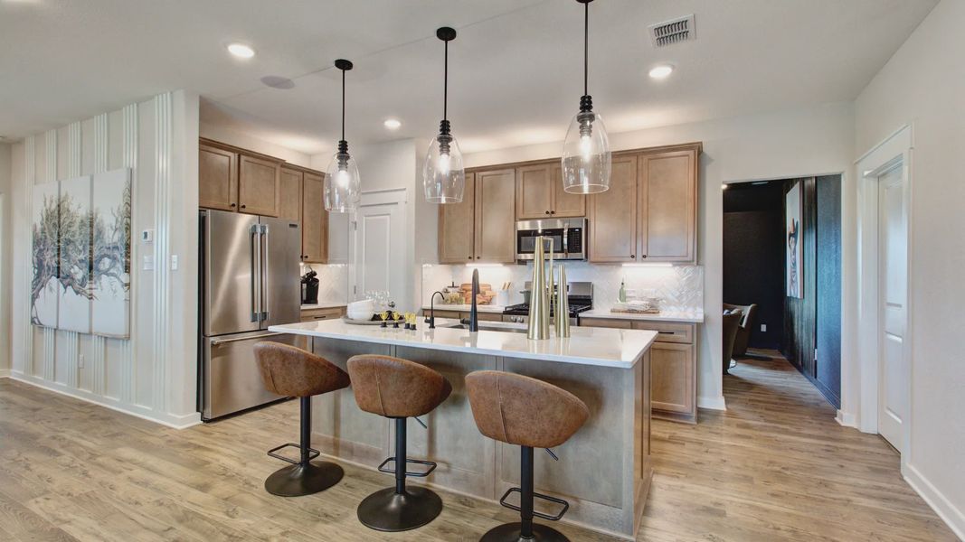 Elegant pendant lighting and chic cabinetry elevate the Prairie Green kitchen ambiance.