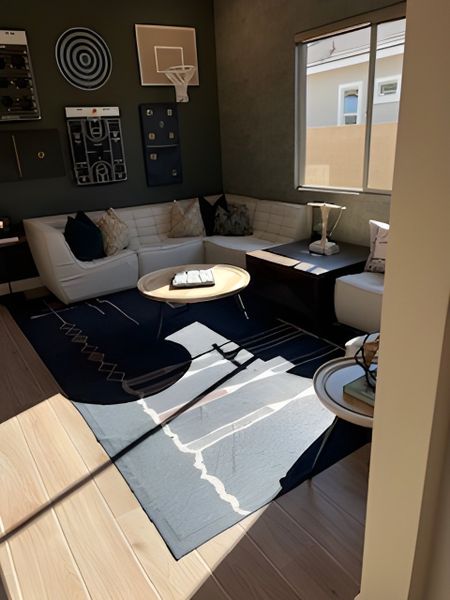 A cozy recreation room with a stylish sectional, playful wall decor, and abundant natural light.