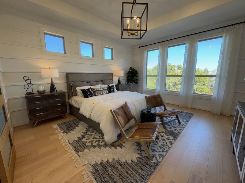 A spacious bedroom with modern decor, featuring a cozy bed, stylish chairs, and large windows offering plenty of natural light. A spacious bedroom with modern decor, featuring a cozy bed, stylish chairs, and large windows offering plenty of natural light.