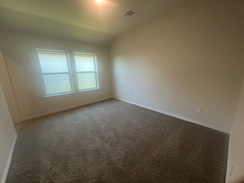 A cozy, carpeted room with natural light from double windows, featuring neutral walls and a simple, clean design. A cozy, carpeted room with natural light from double windows, featuring neutral walls and a simple, clean design.