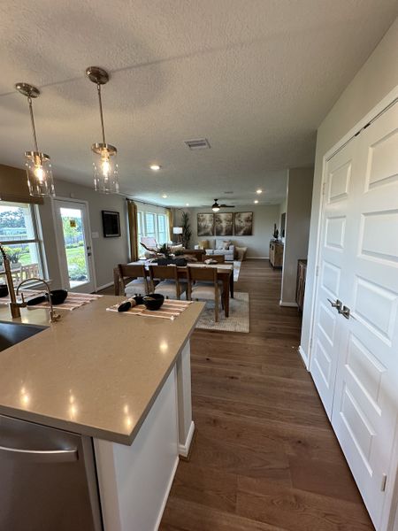An open-concept living area with a sleek kitchen, elegant dining, and cozy seating, featuring warm wood flooring and chic lighting.