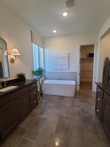 A modern bathroom featuring a sleek bathtub, dark vanity, and elegant lighting, with spacious tile flooring. A modern bathroom featuring a sleek bathtub, dark vanity, and elegant lighting, with spacious tile flooring.