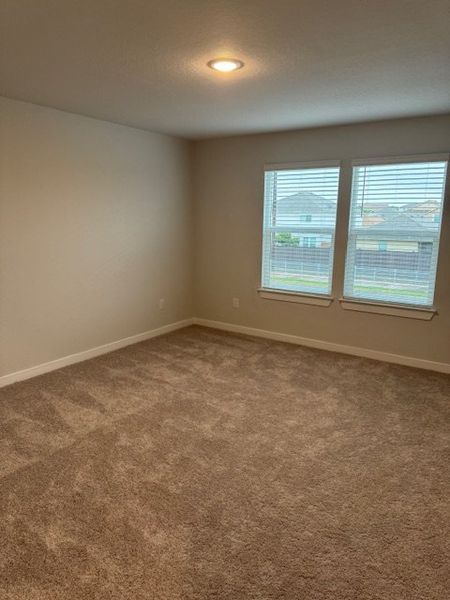 Cozy carpeted room with neutral walls, recessed lighting, and two large windows for natural light. Cozy carpeted room with neutral walls, recessed lighting, and two large windows for natural light.