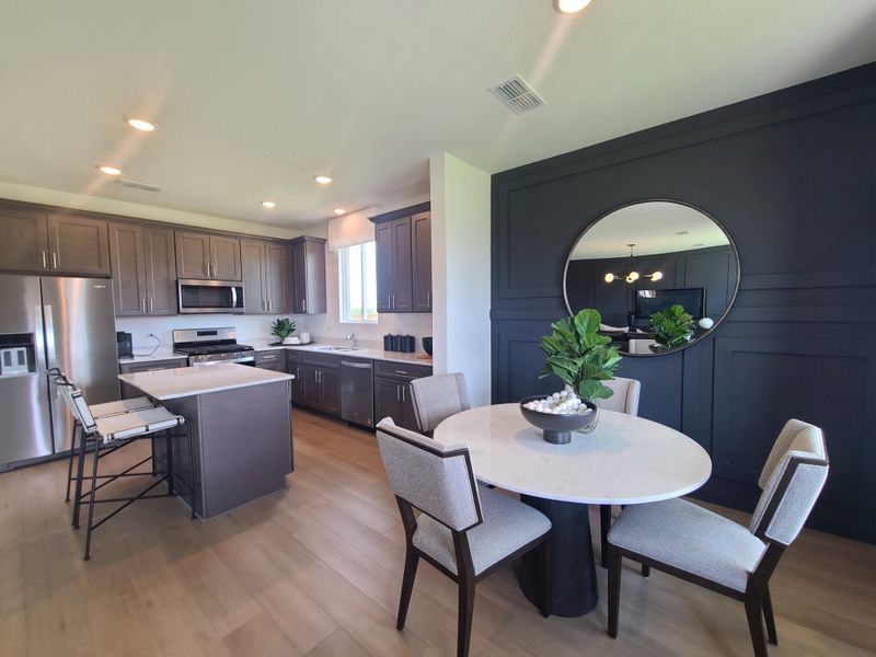 A modern kitchen with sleek cabinetry, stainless steel appliances, and a cozy dining area featuring a circular mirror. A modern kitchen with sleek cabinetry, stainless steel appliances, and a cozy dining area featuring a circular mirror.