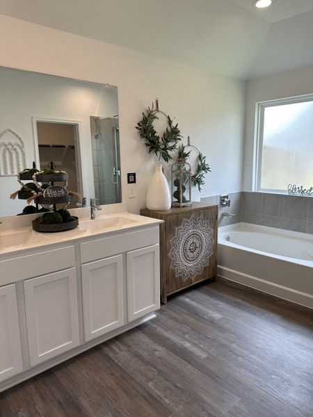 A modern bathroom with a cozy tub, decorative accents, and sleek white cabinetry.