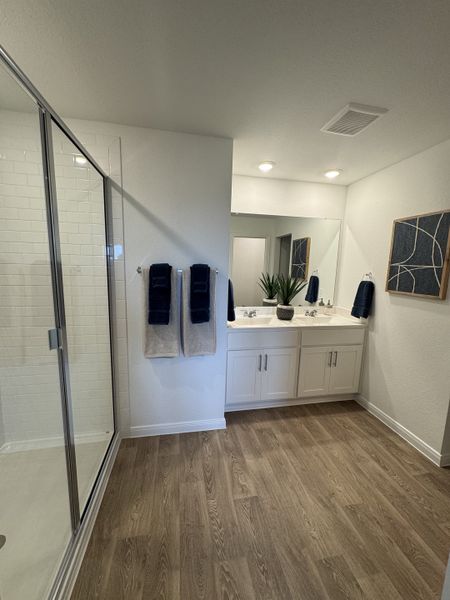 A modern bathroom with a spacious shower, dual sinks, sleek wood floors, and elegant decor. A modern bathroom with a spacious shower, dual sinks, sleek wood floors, and elegant decor.