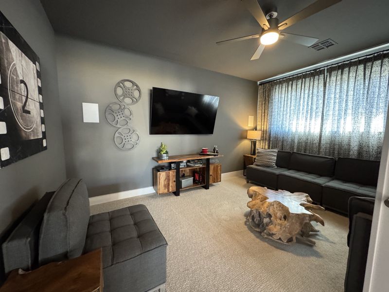 A cozy media room with plush gray seating, unique wood coffee table, and film-inspired decor for style and comfort.