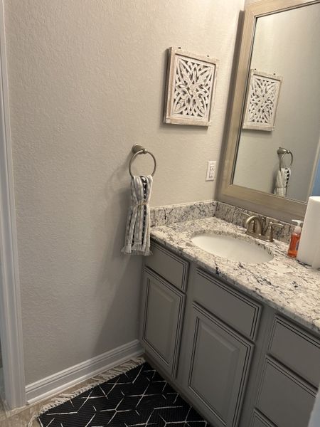 A chic bathroom with a granite countertop, elegant gray cabinetry, and tasteful wall decor. A chic bathroom with a granite countertop, elegant gray cabinetry, and tasteful wall decor.