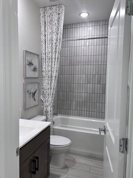 A sleek bathroom featuring a modern vanity, elegant artwork, and vertical tile accents in the shower area.