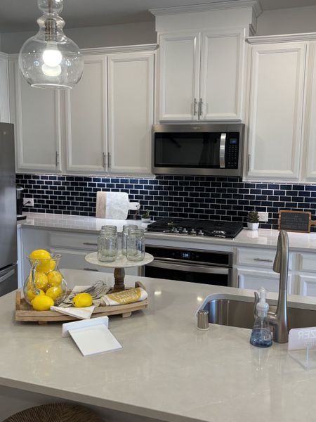 A modern kitchen with white cabinetry, a sleek tile backsplash, and stainless steel appliances.