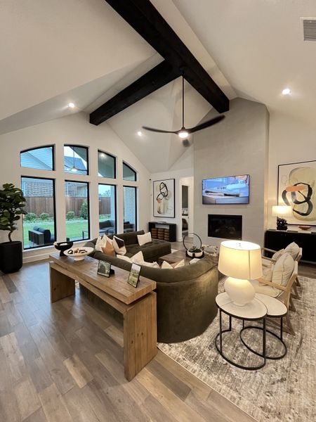 A cozy living room featuring vaulted ceilings with wooden beams, a plush curved sofa, and elegant modern decor.