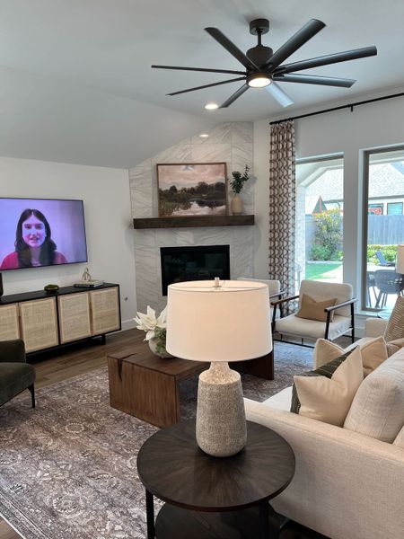 A cozy living room with a modern ceiling fan, elegant fireplace, and plush seating, perfect for relaxation.