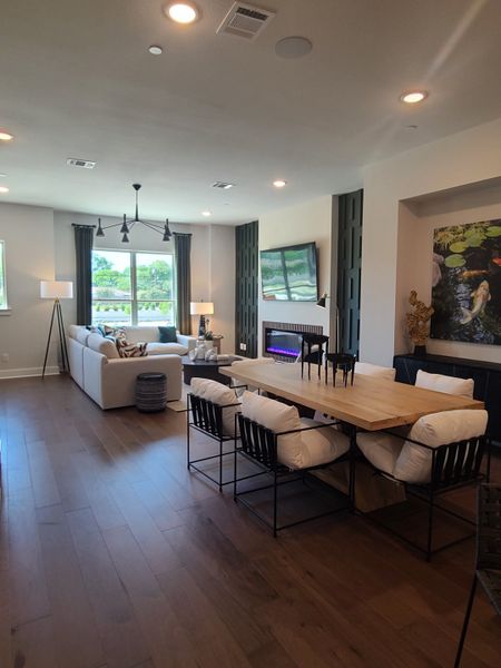A cozy living-dining area with hardwood floors, modern lighting, and a sleek fireplace.