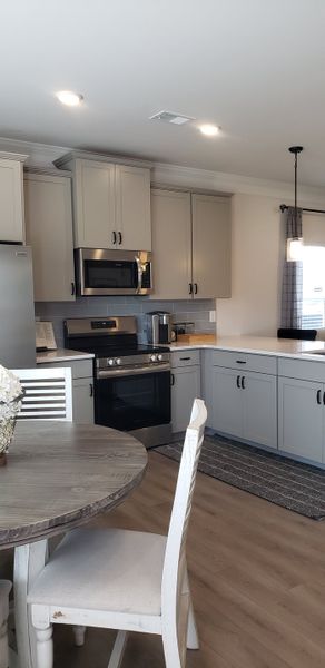 A modern kitchen with gray cabinets, stainless steel appliances, and a cozy dining table setup. A modern kitchen with gray cabinets, stainless steel appliances, and a cozy dining table setup.