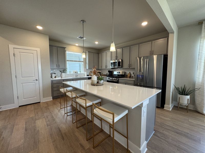 A modern kitchen with sleek gray cabinets, a spacious island, and contemporary lighting.