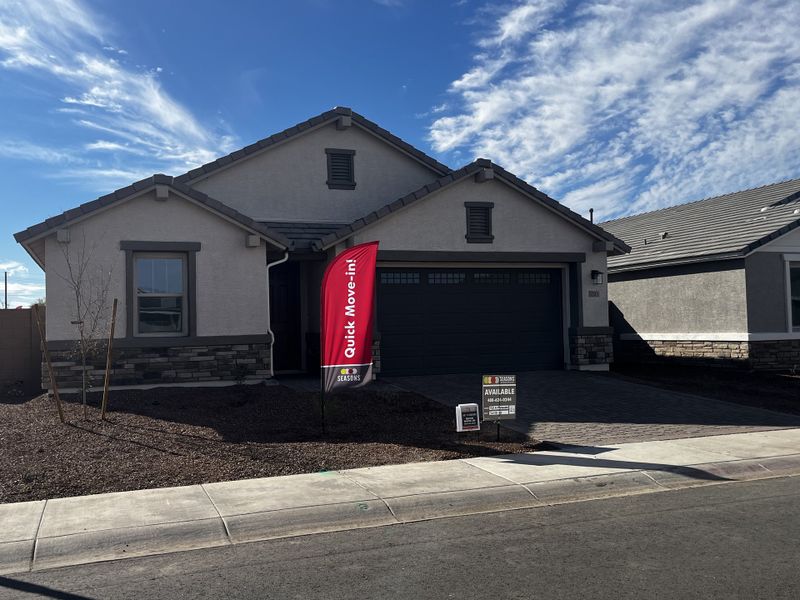 A stylish house with a light garage, stone accents, and and a paved driveway, set in a sunny neighborhood.