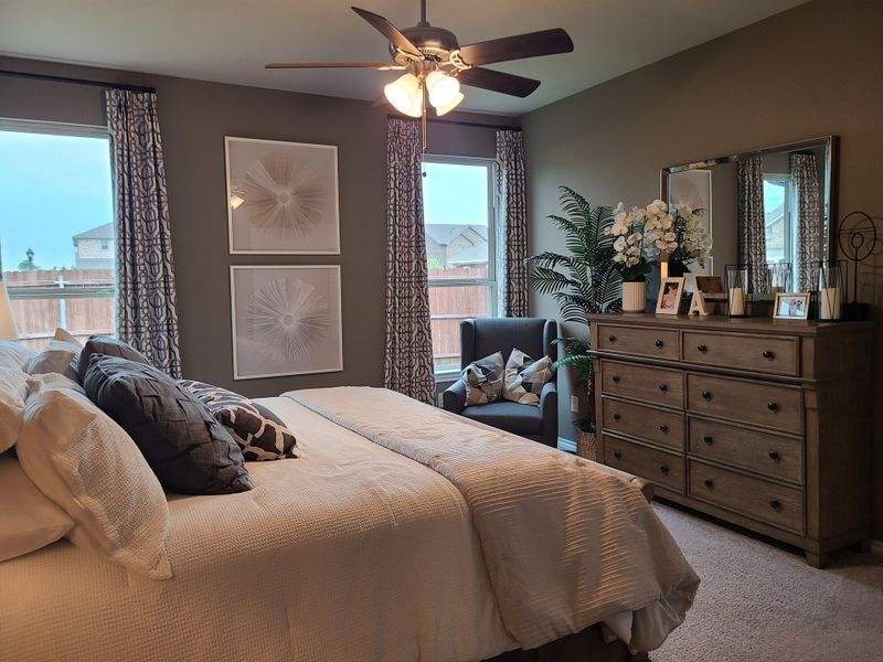 A cozy bedroom featuring elegant decor, a plush bed, and natural light from large windows.